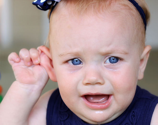 baby holding ear while crying